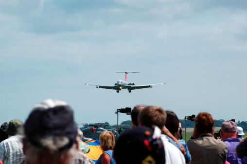 the crowd watches as a airplane lands at an airday in cornwall,england
