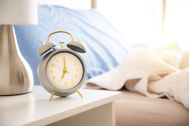 istock Alarm clock standing on night table at sleeping room 1441889739