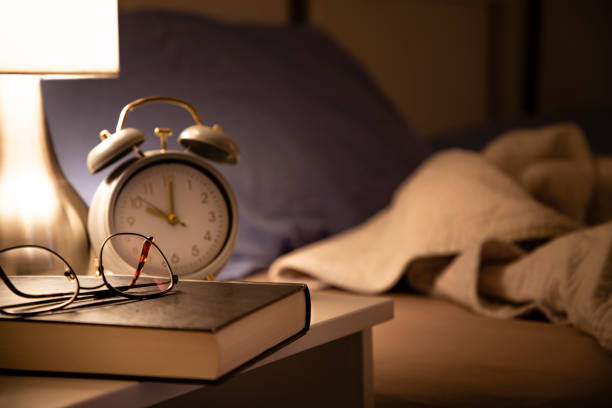ora di andare a dormire: leggere un libro prima di dormire - comodino foto e immagini stock