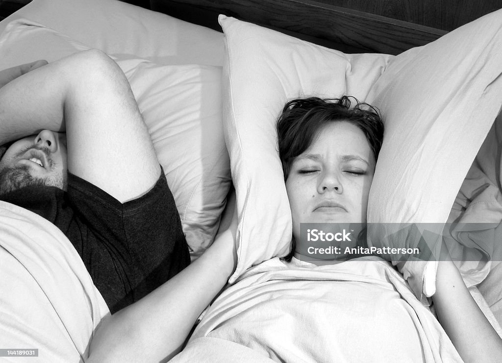 Snoring Couple in bed with woman trying to sleep with man snoring Adult Stock Photo