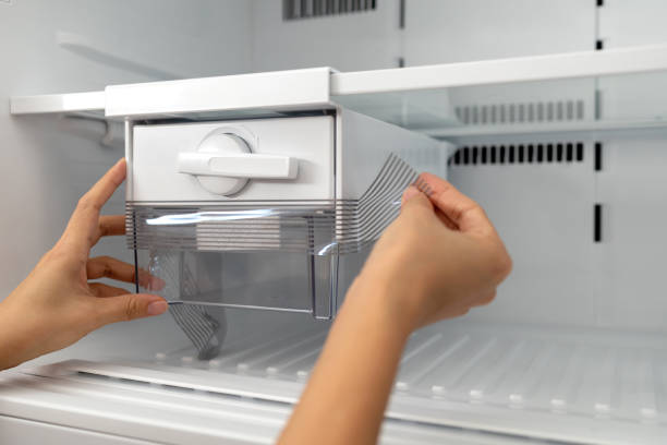 istock Close-Up Hands Removing Plastic Wrap On A Ice Tray In Refrigerator 1441890560