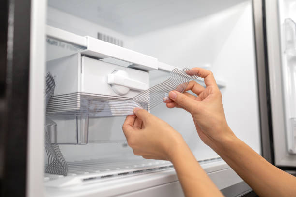 istock Close-Up Hands Removing Plastic Wrap On A Ice Tray In Refrigerator 1441891074