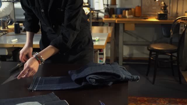 A female tailor seamstress ironing old jeans in a workshop