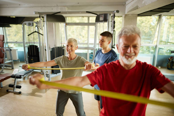 istock Senior couple exercising with personal trainer using resistance band 1441891755