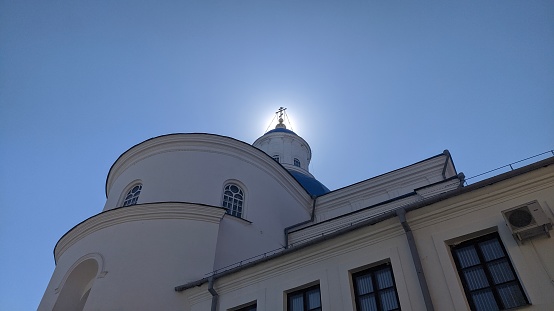 the sun creates a halo on the cross of the church