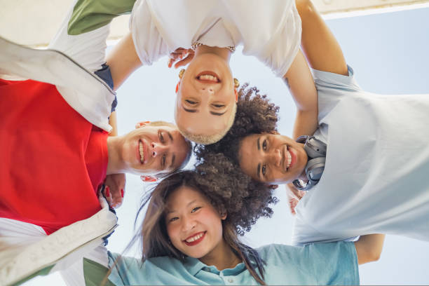istock Low angle view of multiethnic young trendy friends hugging, smiling and making a circle with their heads. 1441892774