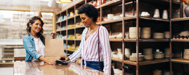 istock Satisfied female shopper doing an NFC payment in a ceramic store 1441895846