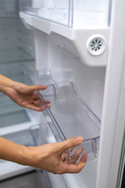 istock Close-Up Female Hands Fixing A Clean Plastic Tray In Refrigerator fridge 1441897316