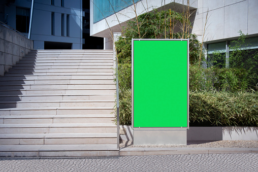 Vertical billboard mockup with green screen in the street next to the stairs
