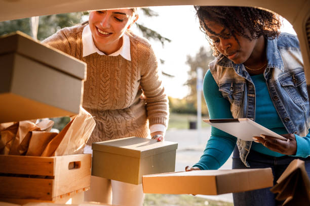 istock Two entrepreneurs loading packages in the car trunk and checking delivery data on labels 1441898775