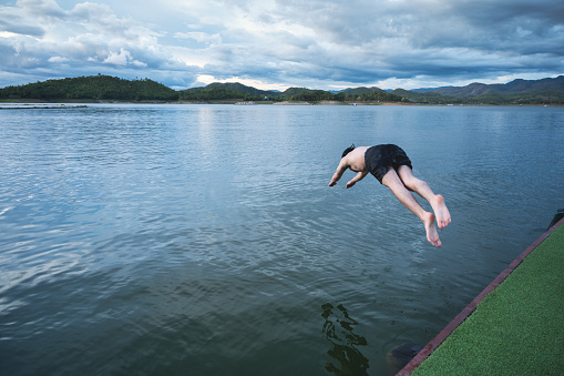 Young man diving into lake on dam in national park
