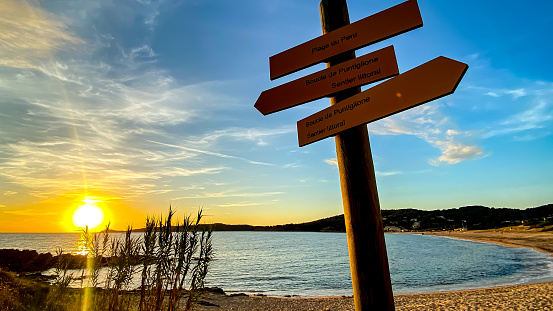 Signpost and the sunset over the Plage de Peru (Peru Beach), in Cargèse - village on the west coast of the island of Corsica, France.