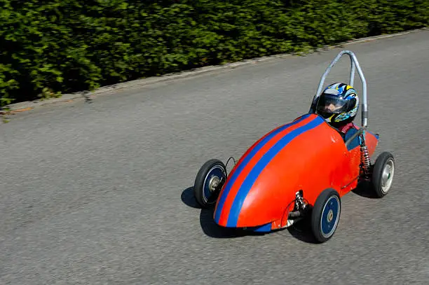 A competitor in a soap-box derby championship hurtles down the road.