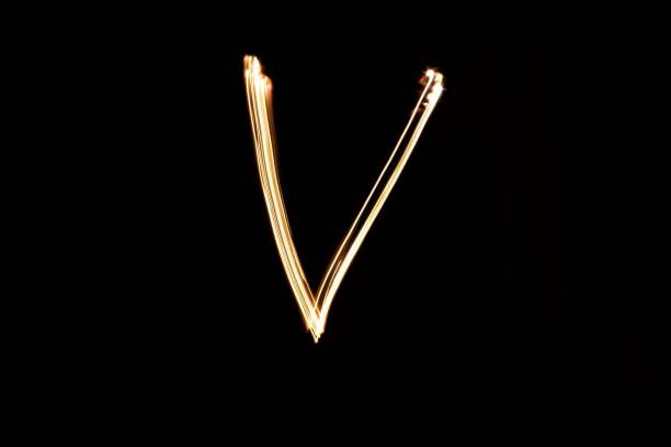 istock Light painting yellow letter V on black background 1441903647