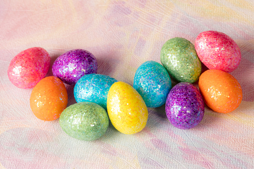 Multi colored Easter eggs lying down on purple paper.