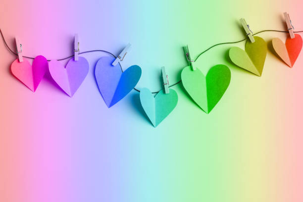 Multi colored paper cut hearts hanging on a clothesline with wooden clothespins. Toned image. Space for copy.