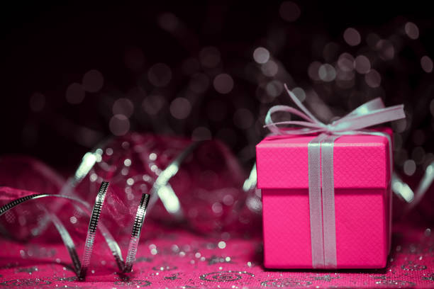 Close-up of a Christmas present (gift box) with defocused christmas lights and decorations in the background.
