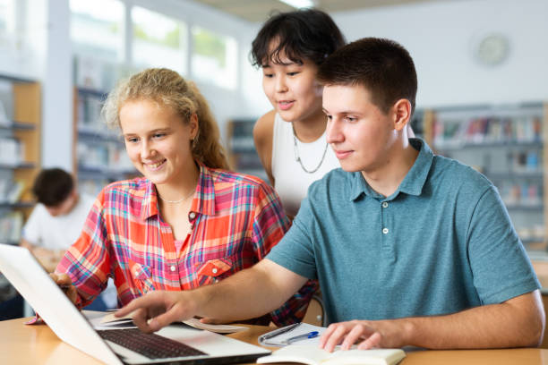 istock Schoolchildren help each other solve the task in school library 1441905143