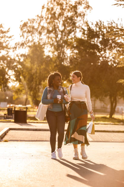 istock Two girlfriends smiling at each other when engaging in interesting conversation during a relaxing walk 1441906124