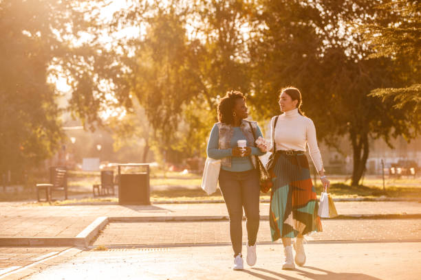 copia lo spazio di due diverse amiche che chiacchierano e camminano lungo la strada della città - campus autumn walking university foto e immagini stock