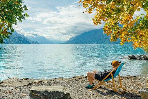 Young man in lounge chair resting near Interlaken lake in Switzerland