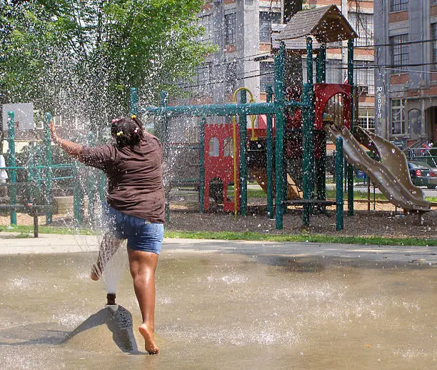 Girl splashing through spray pool at urban park