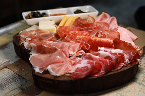 Typical antipasto in an Italian restaurant salami, ham prosciutto, with green and black olives