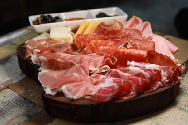 Board Ham Salami Cheese Typical antipasto in an Italian restaurant salami, ham prosciutto, with green and black olives prosciutto brie stock pictures, royalty-free photos & images
