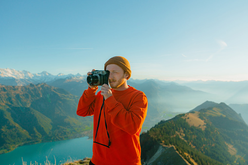 Young Caucasian man photographing on the background of Interlaken in Swiss Alps during his hike