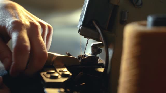 A female tailor hemming old jeans with vintage machine