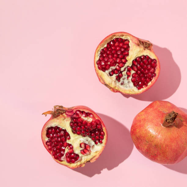 istock Romantic creative layout with whole pomegranate and pomegranate halfs on pink background. Fashion aesthetic fruit concept. Minimal idea. 1441912142