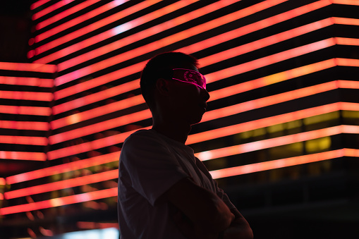 Man wearing smart glowing glasses at night, metaverse, future technology concept