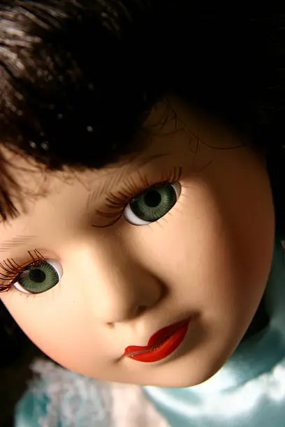 Portait headshot of a porcelain doll in a blue dress