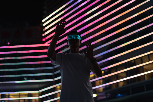 Man wearing smart glowing glasses at night, metaverse, future technology concept