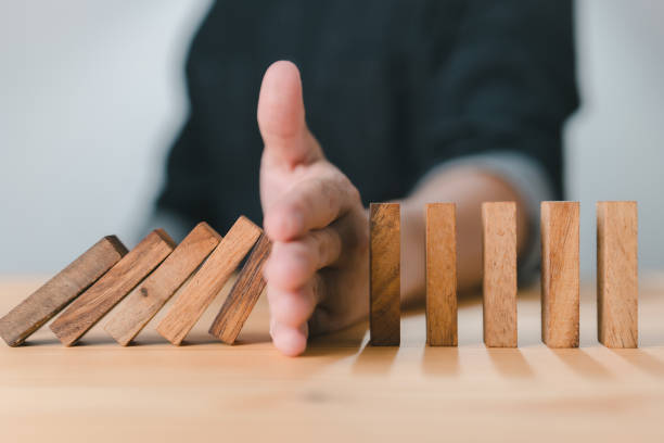 rischio e strategia aziendale: fermare a mano l'effetto domino del blocco di legno di una crisi aziendale o concetto di protezione dal rischio, prevenzione e sviluppo per la stabilità - preventive foto e immagini stock