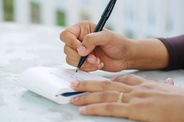 istock women hand writing on notepad sitting on outdoor 1441914603