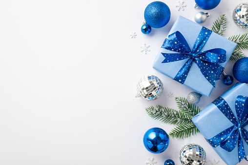 Christmas Eve concept. Top view photo of blue and silver baubles present boxes with ribbon bows disco balls pine branches in snow and confetti on isolated white background with empty space