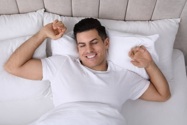 istock Happy man awakening in bed at home, top view 1441918989