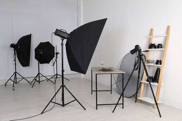 istock Table with stylish dinnerware in front of camera and professional lighting equipment indoors. Photo studio set 1441919015