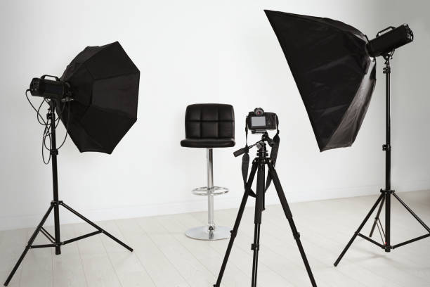 chaise vide devant la caméra et équipement d’éclairage professionnel à l’intérieur. ensemble de studio photo - équipement déclairage photos et images de collection