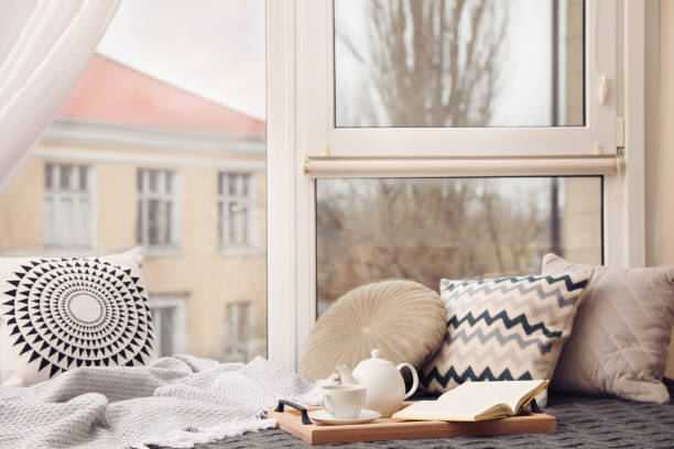 istock Comfortable lounge area with blanket and soft pillows near window in room 1441919160