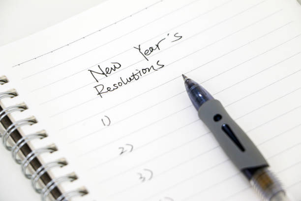 istock Writing new years resolutions, list on white notepad with ballpoint pen. Setting goals for the new year. 1441922010