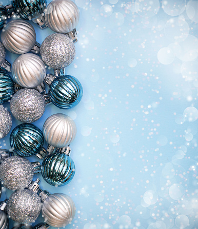 Christmas baubles on blue background. Frame border. Christmas New Year composition background blue grey silver colored. Christmas lights. Minimal concept.