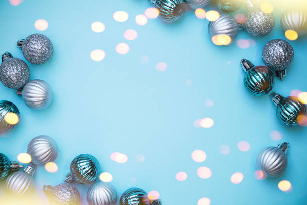 istock Christmas baubles on blue background. Frame border. Christmas New Year composition background blue grey silver colored. Christmas lights. Minimal concept. 1441924236
