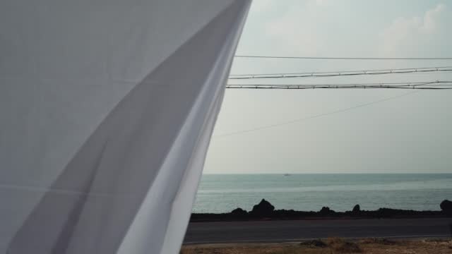 a cloth hanging in the yard with an ocean view flying in the wind