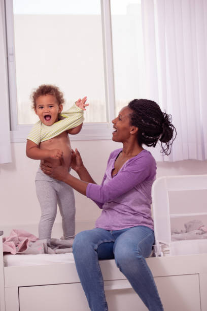 istock Good morning! Awakened mixed race child gets dressed with mom's help. 1441933138