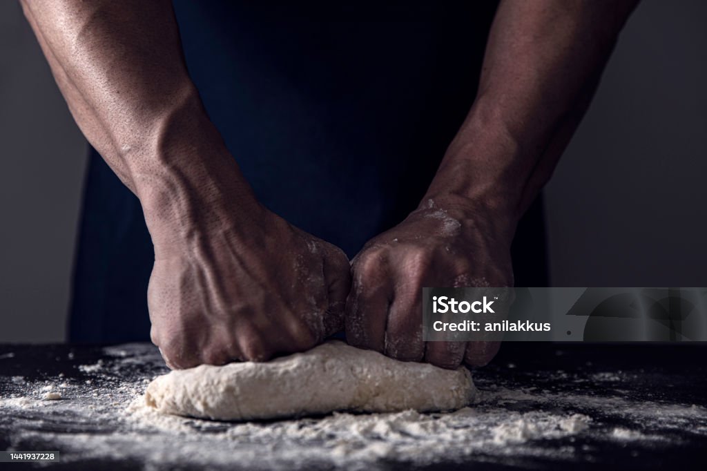 Making Dough Kneading dough with ingredients in domestic kitchen Apron Stock Photo
