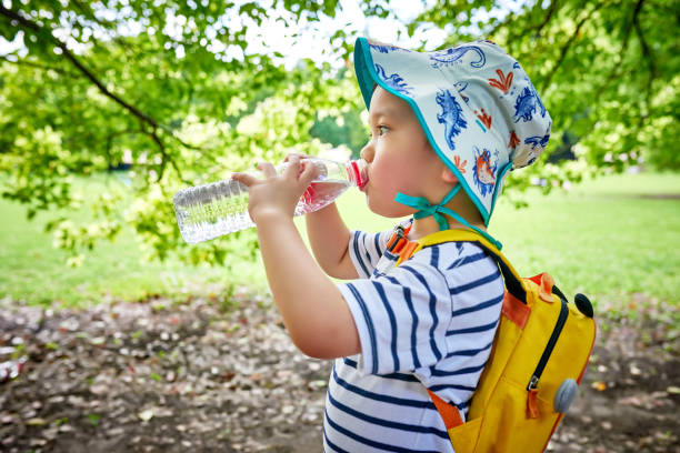 istock Close-up of Little Boy Drinking Water Under Tree 1441937482