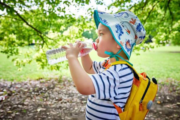 close-up de little boy bebendo água sob a árvore - water child bottle little boys - fotografias e filmes do acervo