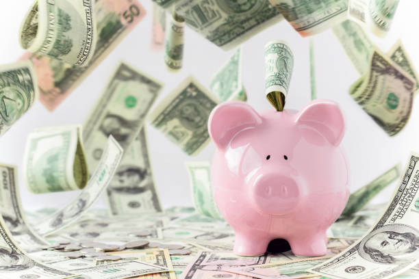Pink piggy bank with money falling flying around Pink piggy bank with American cash money paper bills levitating falling flying around pennies from heaven stock pictures, royalty-free photos & images